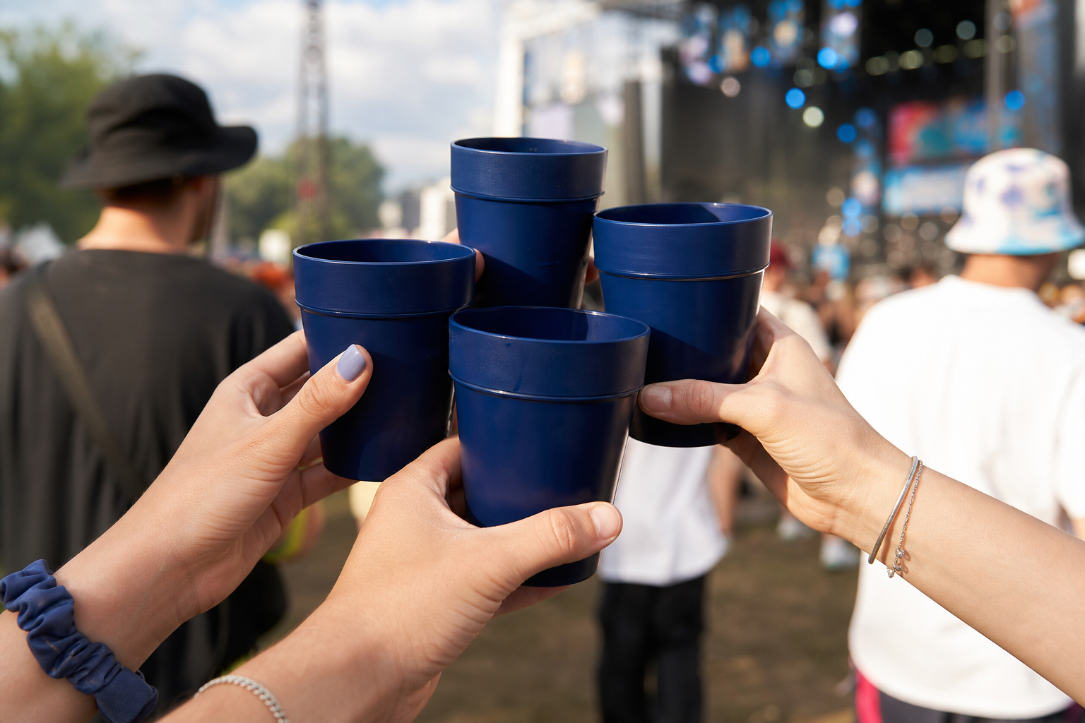 Mehrere Hände halten bedruckte Mehrwegbecher mit Unternehmenslogo auf einem belebten Outdoor-Event.